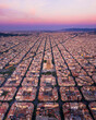 © AmazingAerialAgency - Aerial view of the beautiful Basilica de la Sagrada Familia amidst a sprawling cityscape at sunset, Barcelona, Spain.