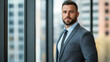 © Kornwit - A business professional standing by a large window, wearing a sharp suit, symbolizing professionalism and confidence