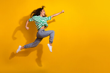 Wall Mural - Full body portrait of nice young girl jump run empty space wear striped t-shirt isolated on yellow color background