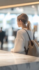 Poster - Young woman is sitting in an airport terminal, waiting for her flight. She is looking at the departures board, checking the status of her flight