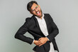 © Andrii Iemelianenko - Indian businessman touching injured sore back, backache, suffering lower lumbar discomfort, muscle pain of overwork, pinched nerve. Male Arabian man guy in formal suit isolated on gray background