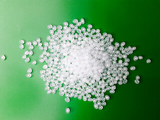Virgin polypropylene plastic granules on a green background, this polymer is one of the main ingredients in the food grade plastic industry.