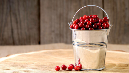 Ripe lingonberries in a decorative bucket on a wooden background