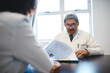 © peopleimages.com - Mature, doctor and clipboard in consultation with patient for medical report, healthcare diagnosis and test results. Medicine, people or paperwork with filing health insurance in clinic for treatment