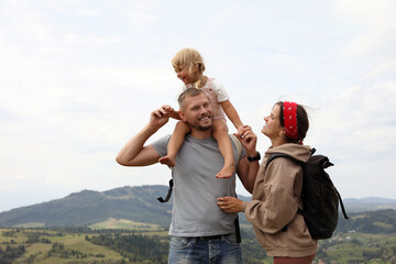 Poster - Happy family with backpacks travelling in mountains, space for text. Active tourism