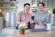 © ultramansk - An elderly couple sits together in their cozy living room, smiling and enjoying a moment as they look at something on a smartphone. Their warmth and affection capture a peaceful home atmosphere.