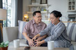 © ultramansk - An elderly couple sits in their living room. The man holds his knee, appearing to be in discomfort, while his partner offers support. The image conveys care, concern, and the bond between the couple.