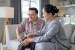 © ultramansk - An elderly couple sits in their living room. The man holds his knee, appearing to be in discomfort, while his partner offers support. The image conveys care, concern, and the bond between the couple.