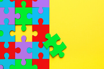 Wall Mural - Many colorful puzzle pieces on yellow background, top view. Symbol of autism