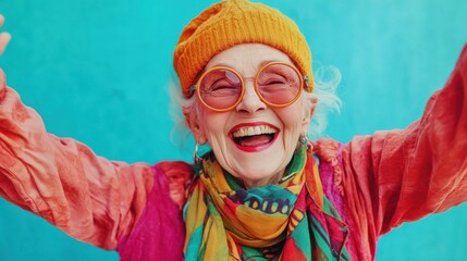 Wall Mural - smiling old lady with round hipster glasses and a colorful scarf, striking a playful pose against a bold turquoise background