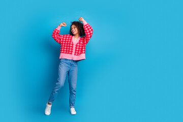 Wall Mural - Portrait photo of american beautiful girl with curly hair wearing red stylish cardigan discotheque dancing isolated on blue color background