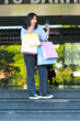 © M Alfan Setyawan - vertical shoot of shocked asian woman holding shopping bag and smartphone covering her mouth while walking on stairway in front of city mall, outdoors