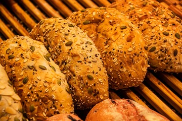 Assorted seeded bread rolls on a wooden rack.