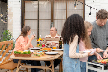 Grandfather, parents, and the teenage girls are all having dinner together at home