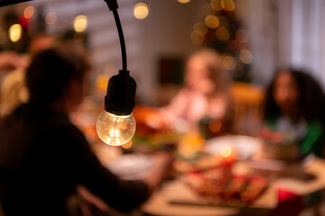 Grandfather, parents, and the teenage girls are all having dinner together at home on Christmas night