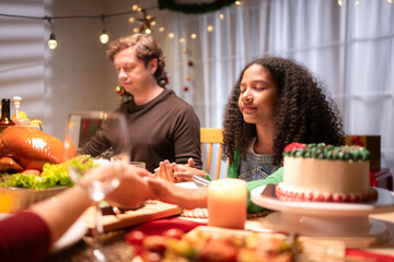 Grandfather, parents, and the teenage girls are all having dinner together at home on Christmas night