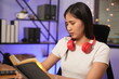 © panomporn - Asian woman listening to cheerful music at the office