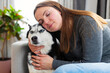 © spyrakot - Woman cuddling Siberian husky at home