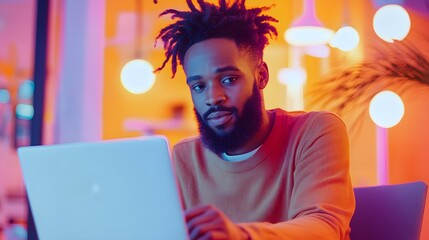 Poster - A man with dreadlocks sitting at a computer, lit in neon colors.