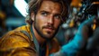 © Prostock-studio - A young man with long hair and a beard attentively repairs machinery in an industrial workshop, showcasing his skill and concentration in the warm afternoon light.