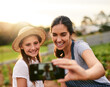 © FotoPush/peopleimages.com - Woman, girl and happy on farm for selfie, social media post and agriculture. Family business, mother and daughter with smile for photography, website update and connectivity in Colombia countryside