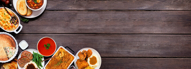 Wall Mural - Cozy comfort food corner border. Above view over a dark wood banner background. Meatloaf, stew, pot pie, mac and cheese, grilled cheese, soup, fried chicken, shepherds pie and warm sides. Copy space.