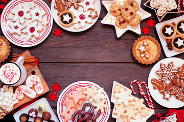 Poster - Christmas holiday cookies and desserts frame. Top down view on a dark wood background. Cookies, tarts, chocolates and hot chocolate tray.