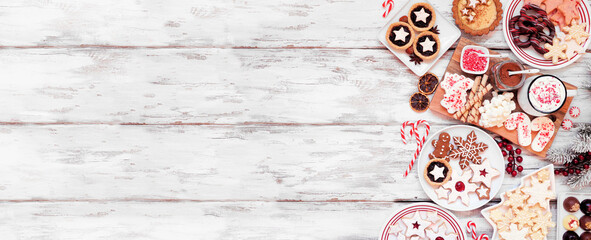 Poster - Christmas holiday cookies and desserts side border. Top down view on a white wood banner background. Cookies, tarts, chocolates and hot chocolate tray.