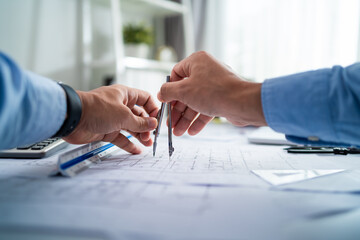 Two men are holding a pair of compasses and drawing on a piece of paper. Concept of collaboration and teamwork, as the two men work together to create something