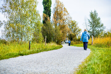 Wall Mural - A man runs in a park with trees and a lake in the background. A woman is walking behind him