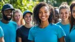 © Nima - A diverse group of smiling volunteers stand together in blue t-shirts, representing community spirit, teamwork, and volunteering.