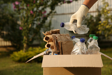 Sticker - Recycling concept. Man putting plastic bottle into cardboard box outdoors, closeup