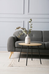 Canvas Print - Stylish sofa and eucalyptus branches in vase on coffee table in room