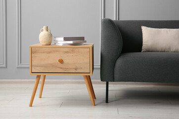 Sticker - Stylish sofa with cushion and books on side table near grey wall