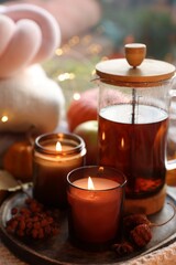 Poster - Burning candles, freshly brewed tea and autumn decor on fabric, closeup