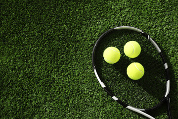 Wall Mural - Tennis racket and balls on green artificial grass, flat lay. Space for text