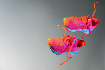 Sticker - Pair of stylish sneakers in air against grey background in neon lights, space for text