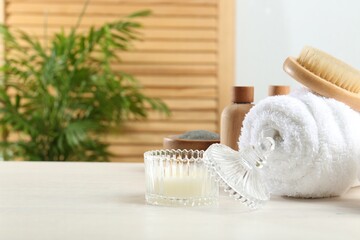 Poster - Spa treatment. Towel, brush, cosmetic products and candle on white table, space for text