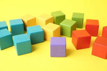 Canvas Print - Many wooden colorful cubes on yellow background, closeup