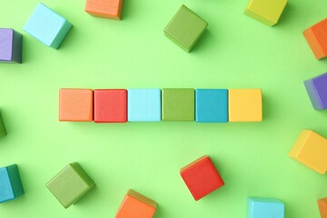 Canvas Print - Many wooden colorful cubes on green background, top view