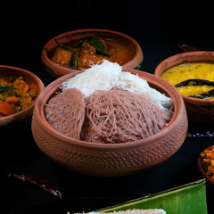 Brown and white String hoppers in clay bowl with lentils curry, Spicy chicken curry and coconut sambal