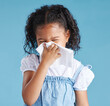 © Flashizzle/peopleimages.com - Girl, child and sneeze with tissue in studio, sick or cold with mucus, cleaning nose and hygiene by blue background. Girl, allergies or hay fever with paper towel for infection, virus and bacteria