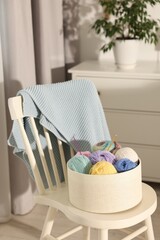 Canvas Print - Box with colorful yarns and crochet hooks on chair indoors