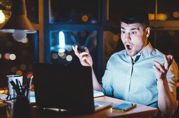 Shocked Businessman With Open Mouth Looking At Laptop Having Unexpected Problem Working In Modern Office At Night