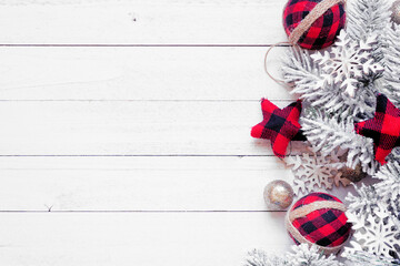 Wall Mural - Christmas side border of red and black gingham ornaments, snowy branches and  gold baubles. Overhead view on a white wood background. Copy space.