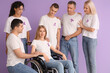 © Pixel-Shot - Young woman in wheelchair and people with lavender awareness ribbons on color background. World Cancer Day
