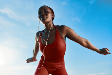 young woman exercising outdoors in a red outfit against a blue sky