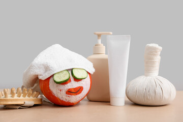 Wall Mural - Funny pumpkin with facial mask, spa accessories and cosmetic products on color table