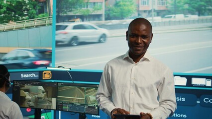 Team leader supervising his team in control center office to work on monitoring traffic by following real time surveillance video. Diverse agency employees examining city streets via CCTV. Camera B.