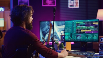 Leinwandbilder - Music producer operating with electronic setup of home studio, recording acoustic guitar sounds. Artist navigating signal processing activity, utilizing digital audio workstation at desk. Camera A.